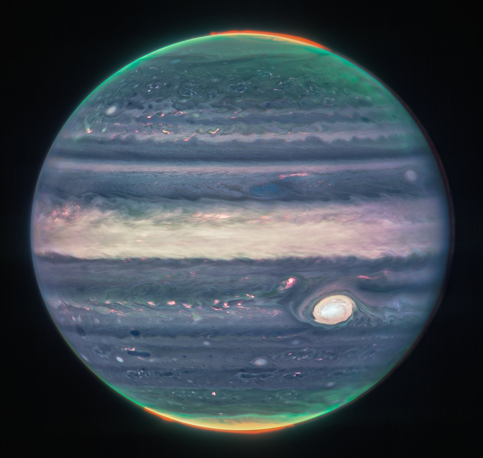 Jupiter dominates the black background of space. The image is a composite, and shows Jupiter in enhanced color, featuring the planet’s turbulent Great Red Spot, which appears white here. The planet is striated with swirling horizontal stripes of neon turquoise, periwinkle, light pink, and cream. The stripes interact and mix at their edges like cream in coffee. Along both of the poles, the planet glows in turquoise. Bright orange auroras glow just above the planet’s surface at both poles.